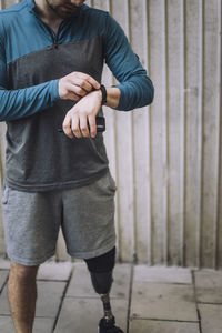 Man with disability checking time on smart watch while standing on footpath