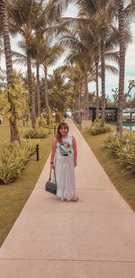 Portrait of woman standing by tree against plants