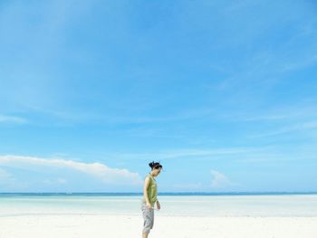 Side view of woman standing at pantai walakiri beach against sky on sunny day