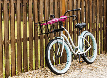 A  beach bike is leaning against a fence in ocean beach, fire island, on a rainy morning.