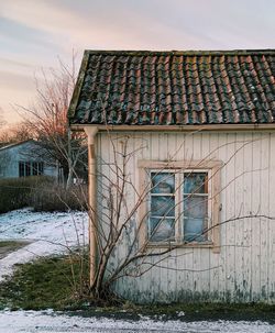 Old house by building against sky during winter