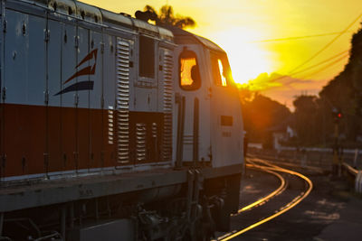 Train on railroad tracks against sky during sunset