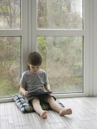 Curious boy watch cartoons on digital tablet. kid sits on floor and uses electronic device. 