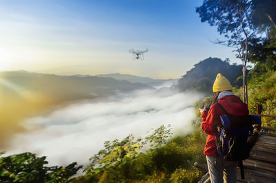 Rear view of man standing on mountain against sky