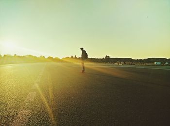 Man skateboarding on road against clear sky at morning