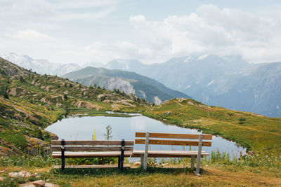 Scenic view of empty bench and mountains against sky