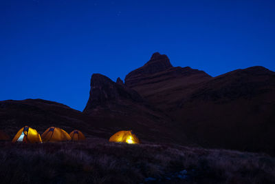 Orange tents set up at the foot of cathedral peak mountain in drakensberg 