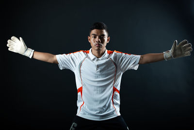 Portrait of young man standing against black background