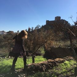 Woman standing by tree against clear sky