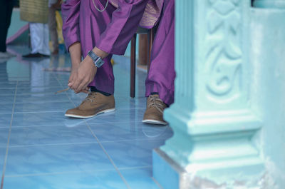 Low section man tying shoelace on tiled floor