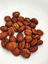 High angle view of roasted coffee beans on white background