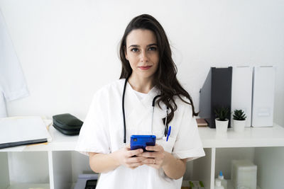 Female doctor holding smart phone in clinic