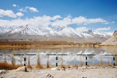 Scenic view of lake by snowcapped mountains against sky