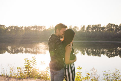 Couple standing by lake against sky