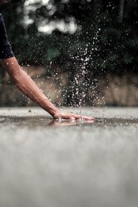 Cropped hand splashing water on road