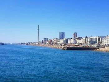 Scenic view of sea and buildings against clear blue sky