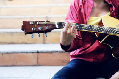 Midsection of man playing guitar