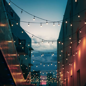 Low angle view of illuminated lights against sky at dusk