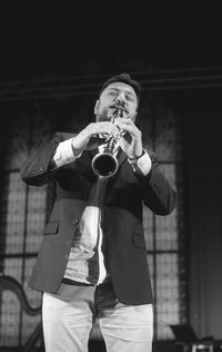 Man playing clarinet while standing at studio