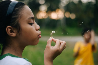 Close-up of girl blowing flower