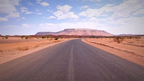 Road leading towards desert against sky