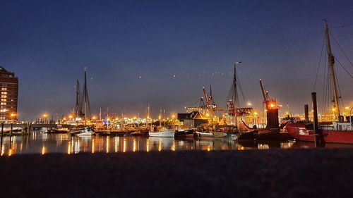 Sailboats moored in harbor at night