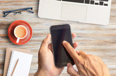 Midsection of man holding coffee cup on table
