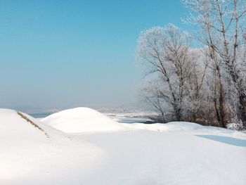 Snow covered landscape against clear sky