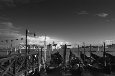 Boats moored in canal against cloudy sky