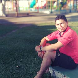 Portrait of smiling young man sitting in park