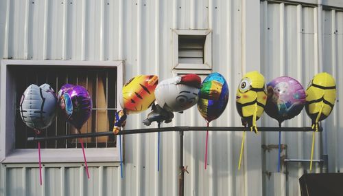 Colorful balloons hanging to pole against house