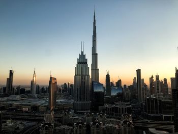 Modern buildings in city against sky during sunset