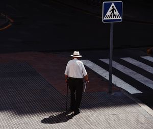 Rear view of man walking on footpath