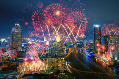 Firework display over illuminated buildings in city at night