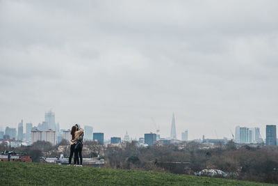 Man photographing cityscape against sky