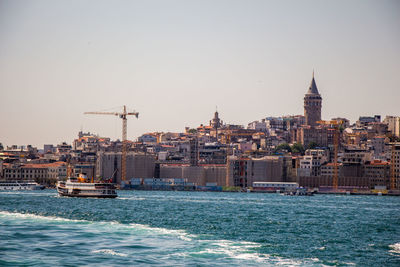 View of buildings by sea against clear sky