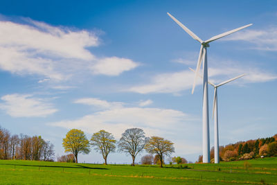 Windmills on field against sky