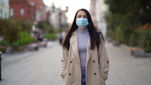 Portrait of woman standing on footpath in city