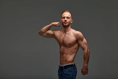 Portrait of shirtless man standing against black background