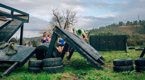 People on bench in field against sky