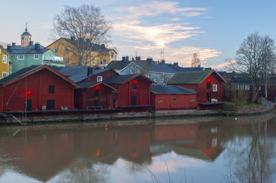 Houses by river and buildings against sky