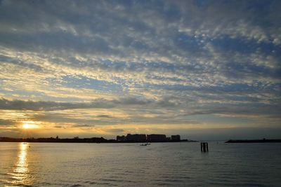 Scenic view of river against cloudy sky during sunset
