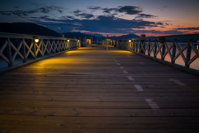 Surface level of footbridge against sky during sunset