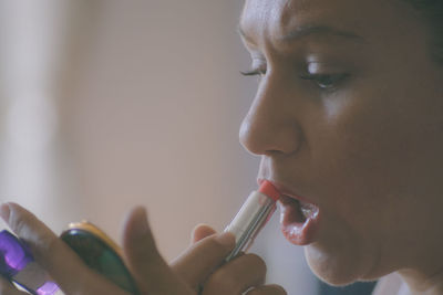 Close-up of woman applying red lipstick