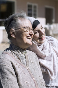 Smiling senior woman and female home caregiver in front of house