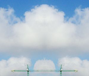 Low angle view of crane against cloudy sky