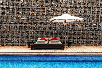 Lounge chairs on wall by swimming pool