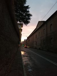 Empty road amidst buildings against sky at dusk