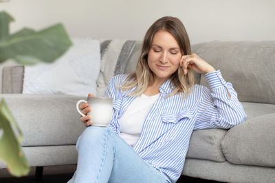 Portrait of young woman sitting on sofa at home