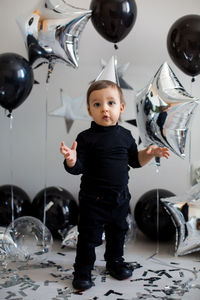Boy in black clothes on his birthday party with balloon and silver stars